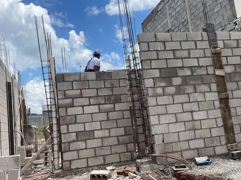 Albañiles levantando muros de block con castillos de acero