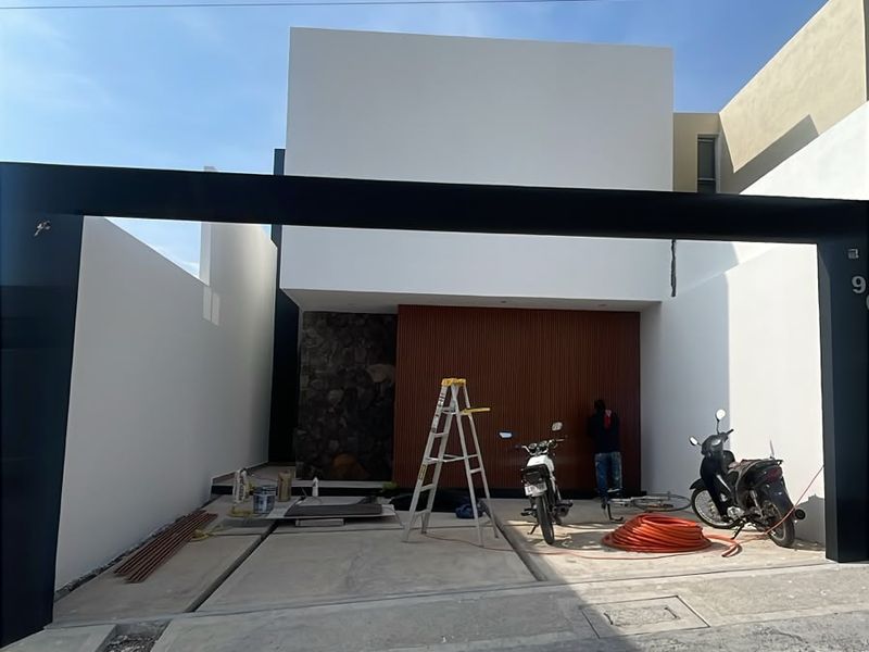 Fachada blanca de dos plantas con marco negro, piedra y celosía de madera