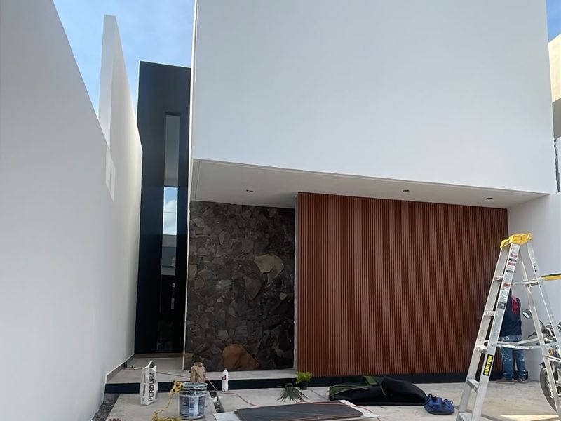 Acceso principal con muro de piedra y celosía de madera