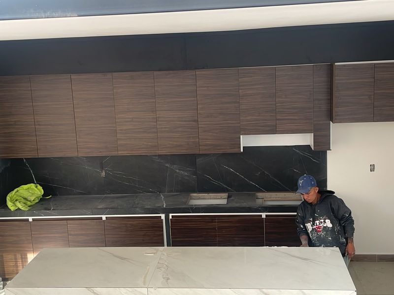 Cocina integral con gabinetes de madera y cubierta tipo mármol negro